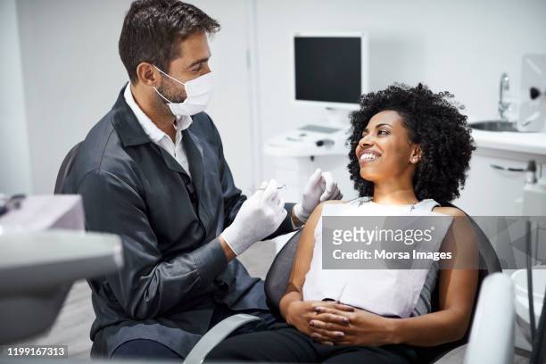 dentist examining smiling female patient in clinic - dentista imagens e fotografias de stock