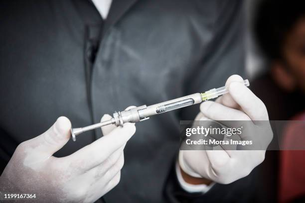 dentist holding anesthetic syringe in clinic - anesthesia stock pictures, royalty-free photos & images