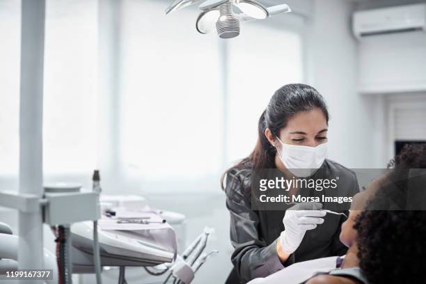 dentista donna che esamina paziente in clinica - igienista dentale foto e immagini stock