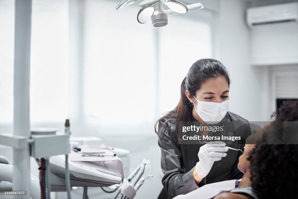 Female dentist examining patient in clinic