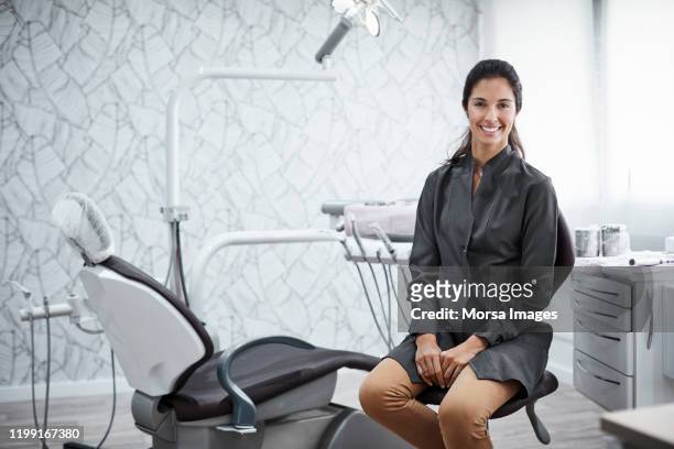 selbstbewusste zahnärztin sitzt in klinik - dental hygienist stock-fotos und bilder
