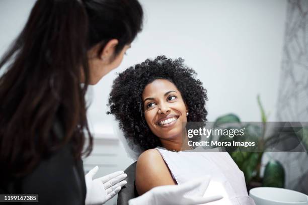 tandarts bespreekt met lachende vrouwelijke patiënt - tandarts stockfoto's en -beelden