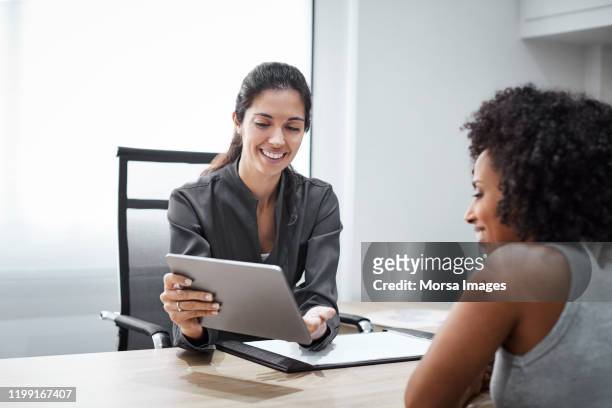 smiling dentist explaining patient over tablet pc - explaining stock pictures, royalty-free photos & images