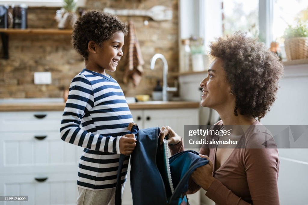 Single black mother packing her small son for school.