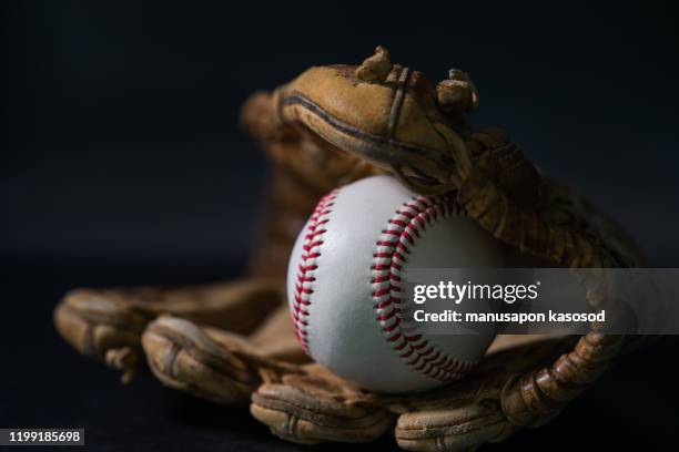 baseball in a glove on black background. - baseball glove stockfoto's en -beelden