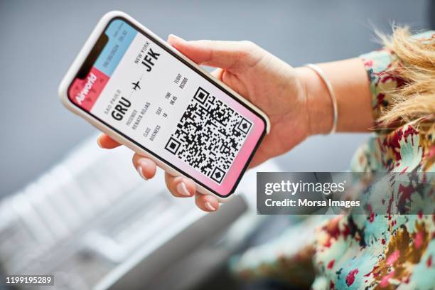 vrouw houdt online boarding pass in mobiele telefoon - phone screen at airport stockfoto's en -beelden