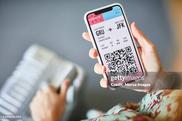 vrouw online vliegticket controleren op mobiele telefoon - phone screen at airport stockfoto's en -beelden