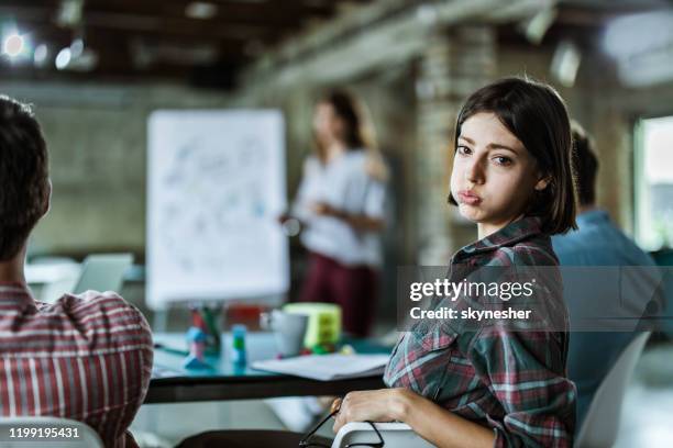 uttråkad kreativ kvinna på en presentation med sina kollegor på kontoret. - boredom bildbanksfoton och bilder