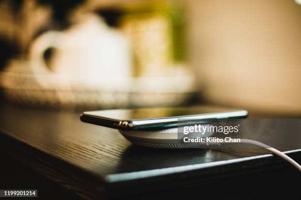 charging mobile phone with wireless charging device in the living room - wireless charger stock pictures, royalty-free photos & images