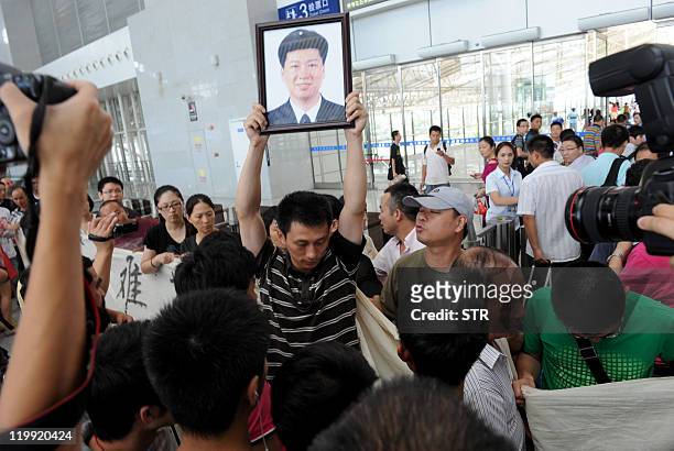 Chinese man holds up a portrait of his relative as family members of victims who died in the July 23 high-speed train collision demontrate in the...