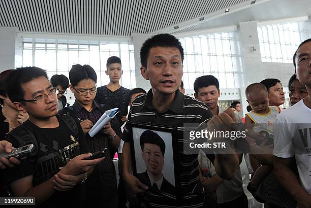 Chinese man holds a portrait of his relative speaks to the media while family members of victims who died in the July 23 high-speed train collision...