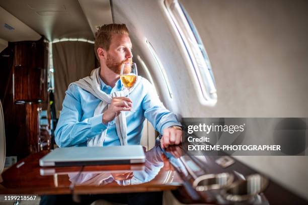 young ceo sitting on a private plane, drinking wine - billionaire stock pictures, royalty-free photos & images