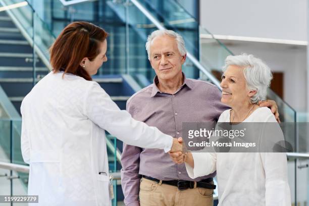 elderly couple visiting doctor in hospital - couple shaking hands with doctor stock pictures, royalty-free photos & images