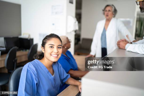 portrait of secretary working at hospital reception - secretary stock pictures, royalty-free photos & images