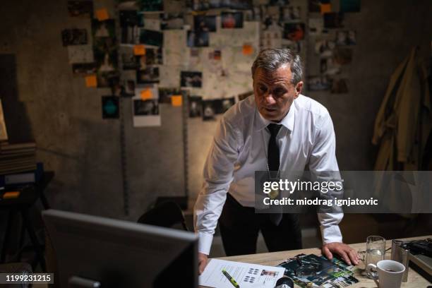 mature police detective looking at computer late at night in his office - detective badge stock pictures, royalty-free photos & images