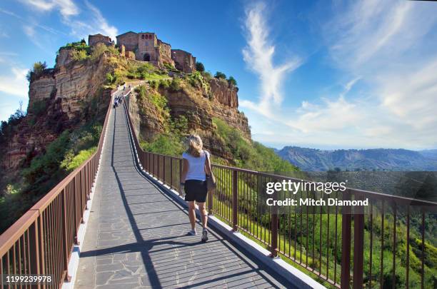 tourist on bridge to  medieval civita di bagnoregio - civita di bagnoregio fotografías e imágenes de stock