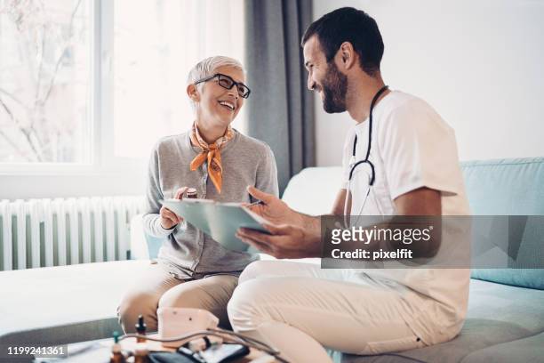 donna anziana che parla con un medico - servizio a domicilio foto e immagini stock
