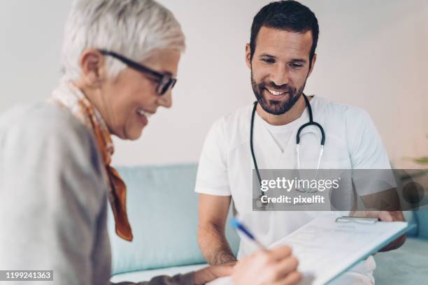 senior woman signing her medical results - medical document stock pictures, royalty-free photos & images