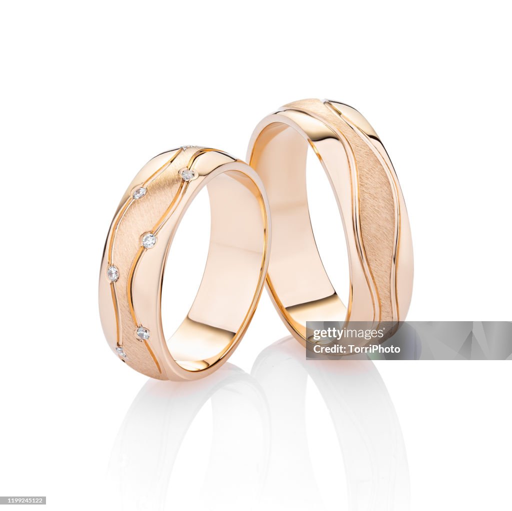 Pair of pink gold wedding rings with diamonds isolated on white background