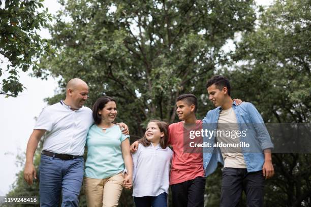 affectionate latin family with three children walking outside and smiling - ten to fifteen stock pictures, royalty-free photos & images