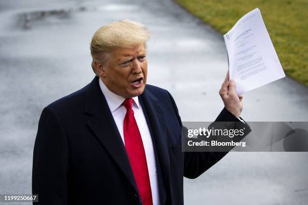 President Donald Trump holds a copy of a U.S. Appeals court ruling as he speaks to members of the media before boarding Marine One on the South Lawn...