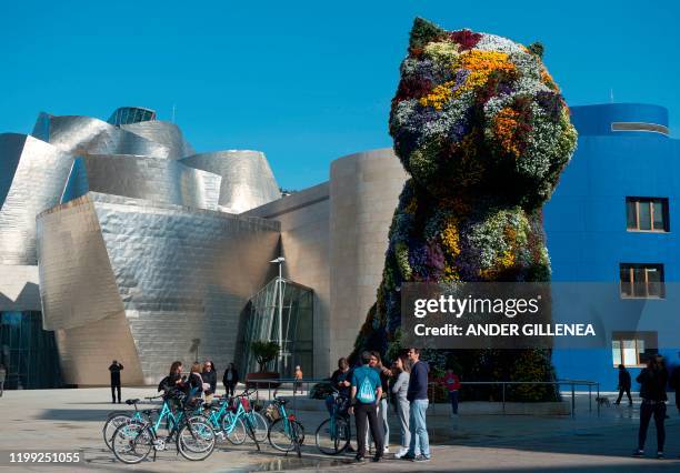 Some people gather next to US artist Jeff Koons' sculpture "Puppy" outside the Guggenheim Bilbao Museum in the Spanish Basque city of Bilbao, on...
