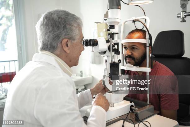 senior doctor examining patient doing eyesight measurement in ophthalmology clinic - eye doctor stock pictures, royalty-free photos & images