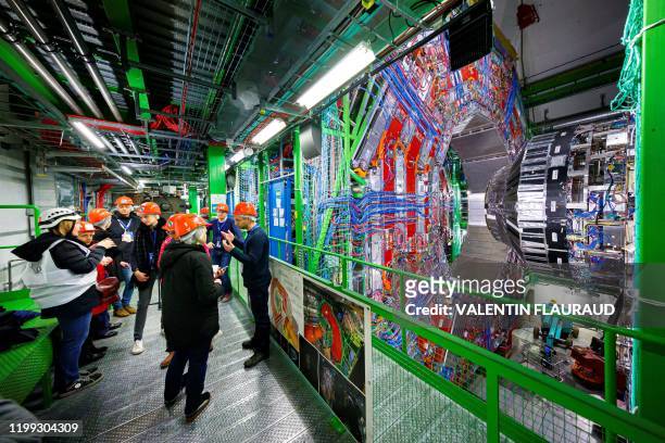 Members of the media receive explanations nexto to the Compact Muon Solenoid detector assembly in a tunnel of the Large Hadron Collider at the...