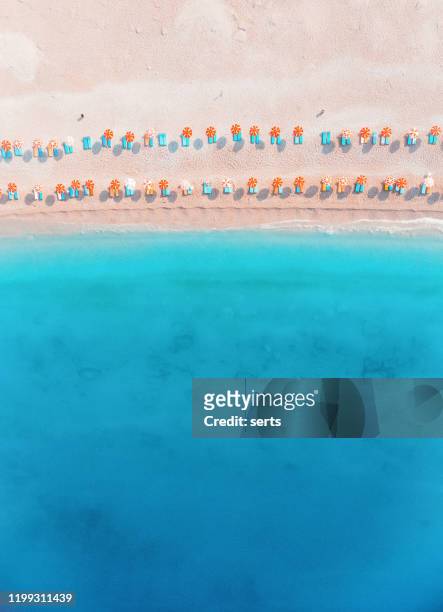 luchtmening van de blauwe overzees en strandkustlijn die met kleurrijke paraplu's worden bezaaid. - beach umbrella sand stockfoto's en -beelden