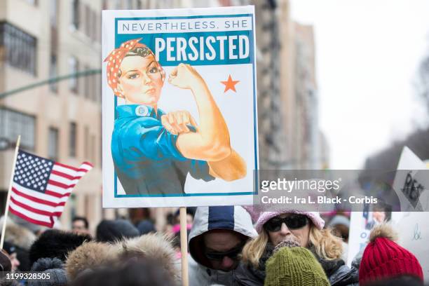 Group of marchers with signs that say "Nevertheless. She Persisted" with Rosie the Riveter and next to an American flag during the Woman's March in...
