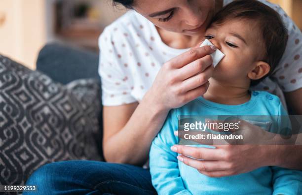 mother helping her baby son to blow his nose - blowing nose stock pictures, royalty-free photos & images