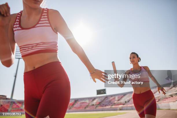 teenage athlethes on a relay race passing relay buton - track and field baton stock pictures, royalty-free photos & images