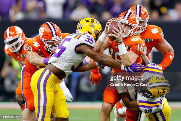 Trevor Lawrence of the Clemson Tigers is sacked by K'Lavon Chaisson of the LSU Tigers and Damone Clark of the LSU Tigers in the College Football...