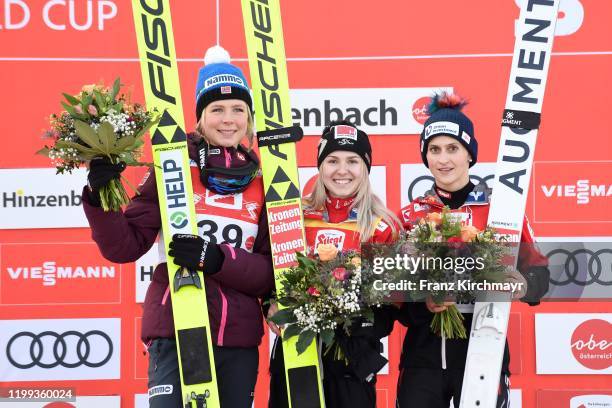 Second place Maren Lundby of Norway, first place Chiara Hoelzl of Austria and third place Eva Pinkelnig of Austria stand on the podium on FIS Ski...