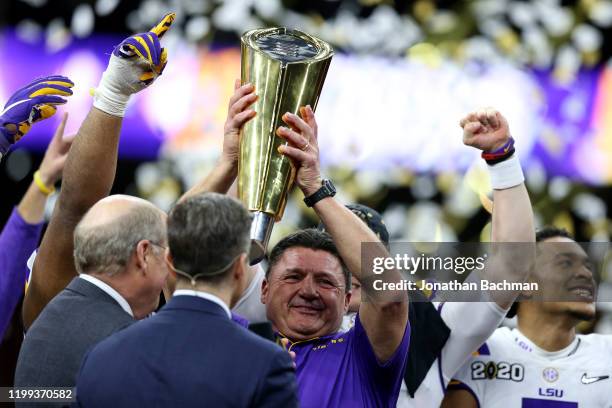 Head coach Ed Orgeron of the LSU Tigers and Joe Burrow of the LSU Tigers celebrate with the trophy after defeating the Clemson Tigers 42-25 in the...
