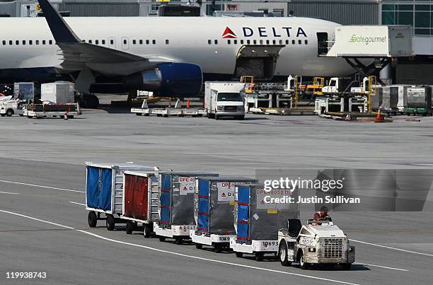 Delta Airlines baggage cart drives by a Delta Airlines plane at San Francisco International Airport on July 27, 2011 in San Francisco, California....