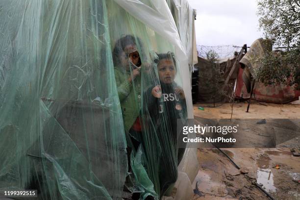 Palestinian children watch the rain from behind nylon sheets covering their family tent, on a rainy day in al-Amal neighbourhood of Beit Lahia in the...