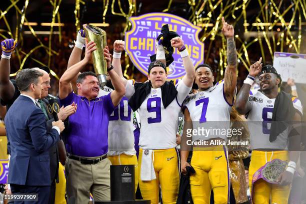 Head coach Ed Orgeron of the LSU Tigers raises the National Championship Trophy with Joe Burrow, Grant Delpit, and Patrick Queen after the College...