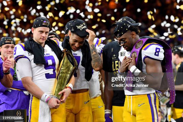 Joe Burrow of the LSU Tigers holds the National Championship Trophy with Grant Delpit, and Patrick Queen after the College Football Playoff National...