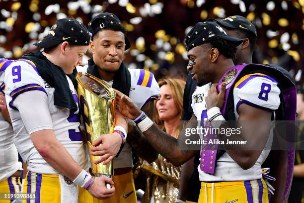 Joe Burrow of the LSU Tigers holds the National Championship Trophy with Grant Delpit, and Patrick Queen after the College Football Playoff National...