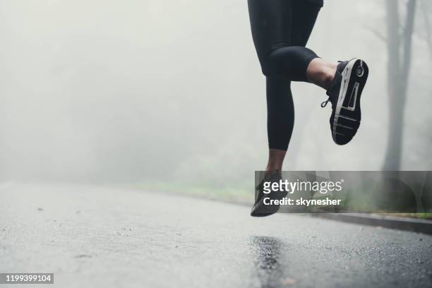 unrecognizable athlete jogging on the road during rainy day. - women taking showers stock pictures, royalty-free photos & images