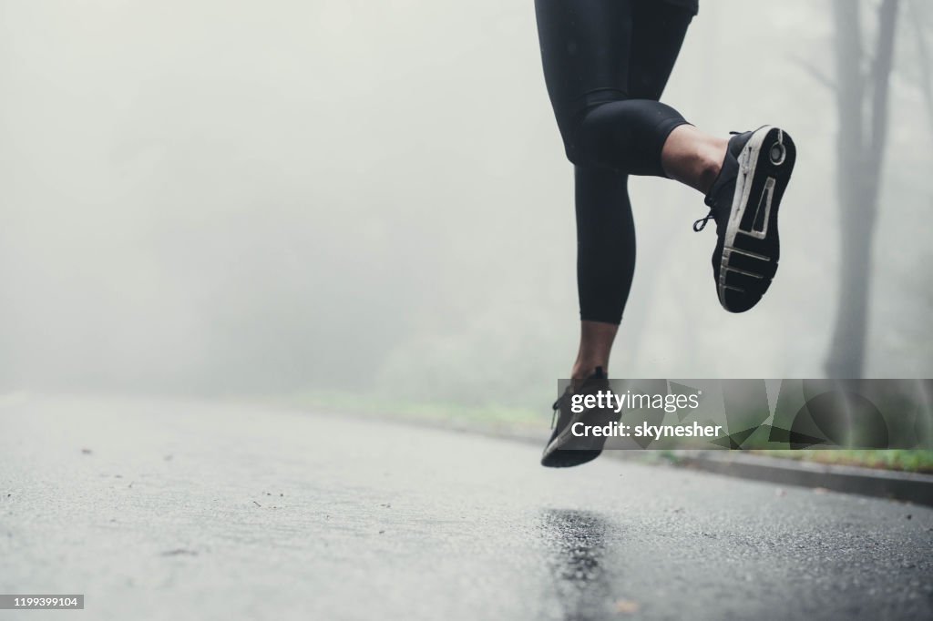 Atleta irreconhecível que movimenta-se na estrada durante o dia chuvoso.