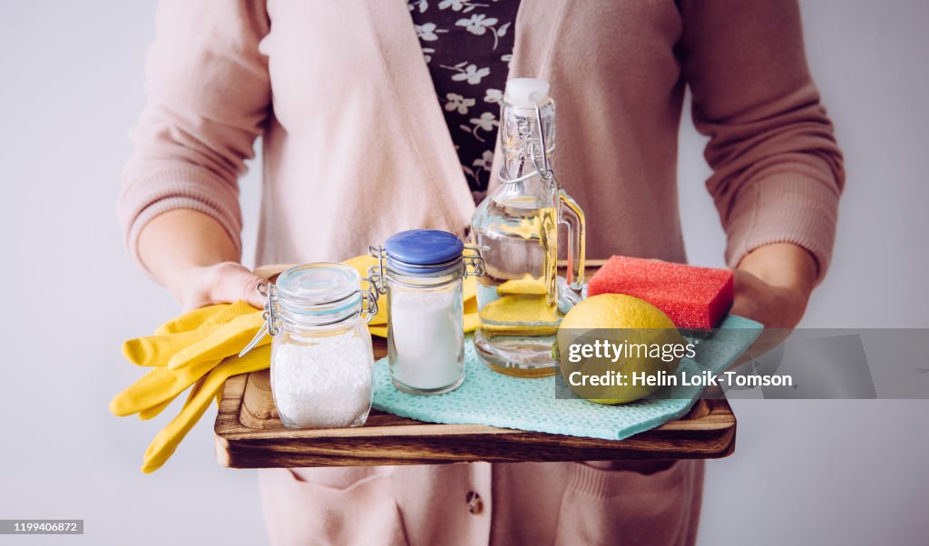 Natural cleaners concept. Woman holding eco friendly home cleaning ingredients, white vinegar, lemon, baking soda, citric acid concept.