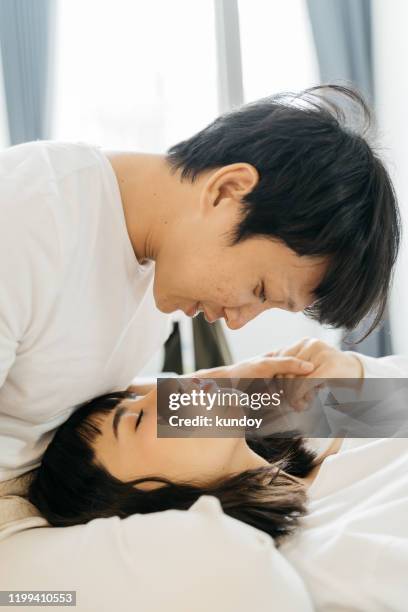 portrait of asian couple sleeping on bed. happy family. love and valentine concept. - asian couple kissing stockfoto's en -beelden