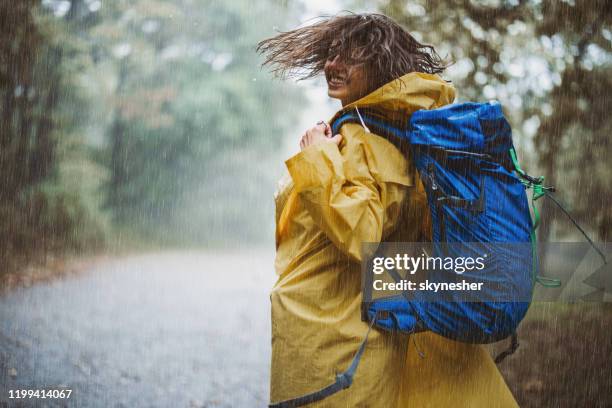 bekymmerslös kvinna i regnrock ha kul medan du springer på en regnig dag. - regnkläder bildbanksfoton och bilder
