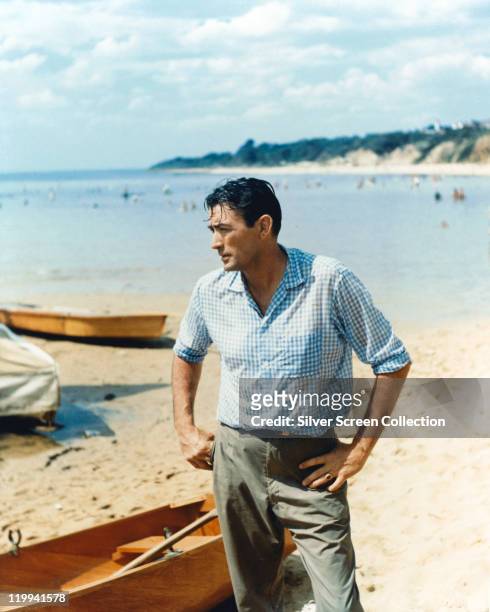 Gregory Peck , US actor, poses on a beach, with various small boats in the background, circa 1958.