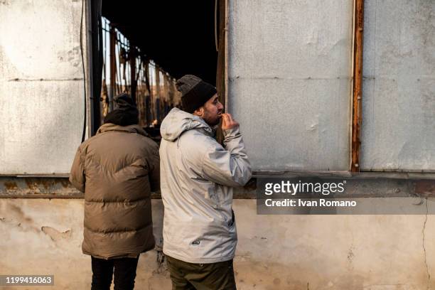 Algerian migrants eats a meal offered by some volunteers inside an abandoned industrial warehouse on January 12, 2020 in Velika Kladuša, Bosnia and...