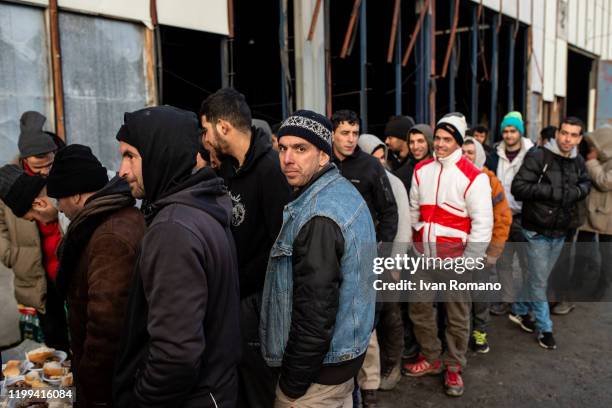 Algerian migrants lined up for a meal offered by some volunteers, near an abandoned industrial warehouse on January 12, 2020 in Velika Kladuša,...