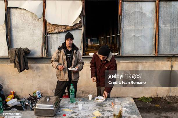 Algerian migrants eats a meal offered by some volunteers inside an abandoned industrial warehouse on January 12, 2020 in Velika Kladuša, Bosnia and...