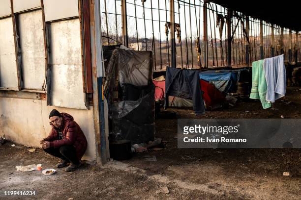 Algerian migrant eats a meal offered by some volunteers inside an abandoned industrial warehouse on January 12, 2020 in Velika Kladuša, Bosnia and...